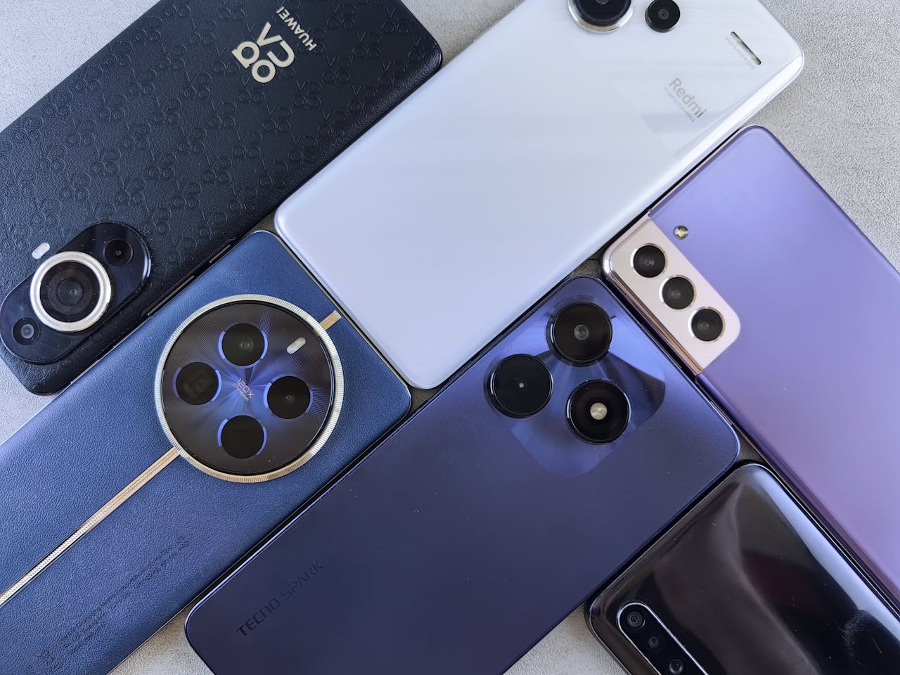 Top view of various modern smartphones showcasing diverse camera designs on flat surface.